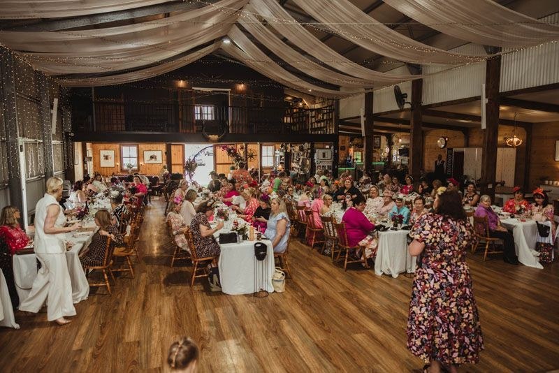 Inside Aberfeldy Barn during a function, with draped ceiling, fairy lights and full tables.