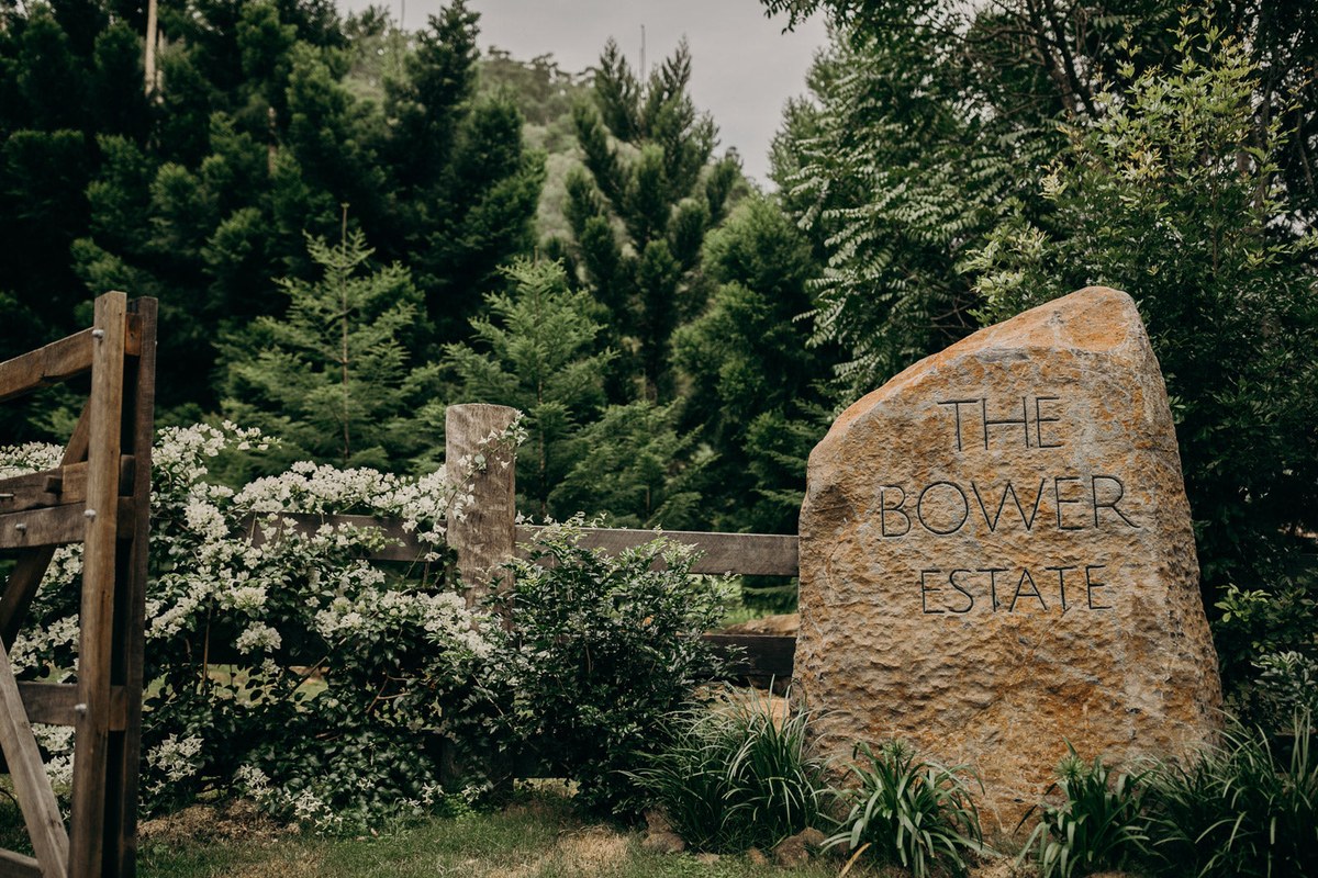 The carved sandstone entrance marker reading The Bower Estate beside a timber fence.