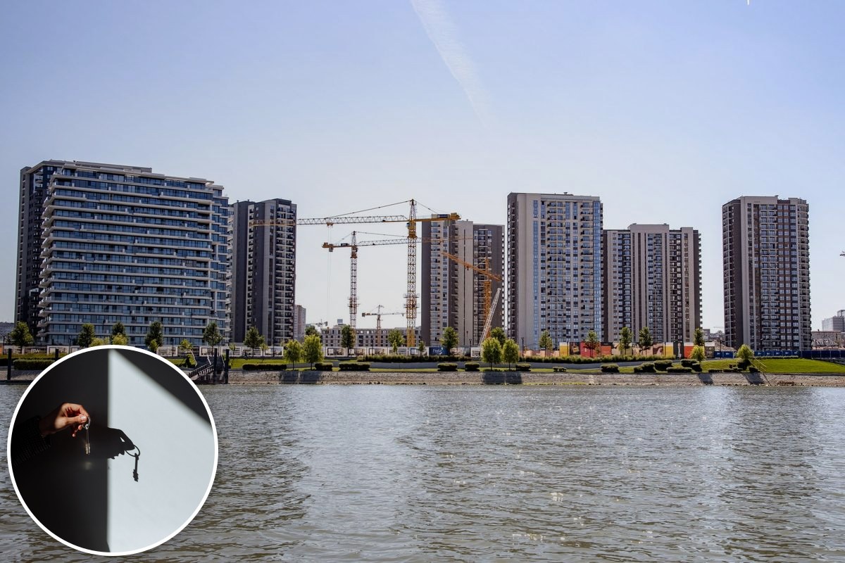 Apartment towers and construction cranes rise beside a river, with an inset photo of a hand holding keys.