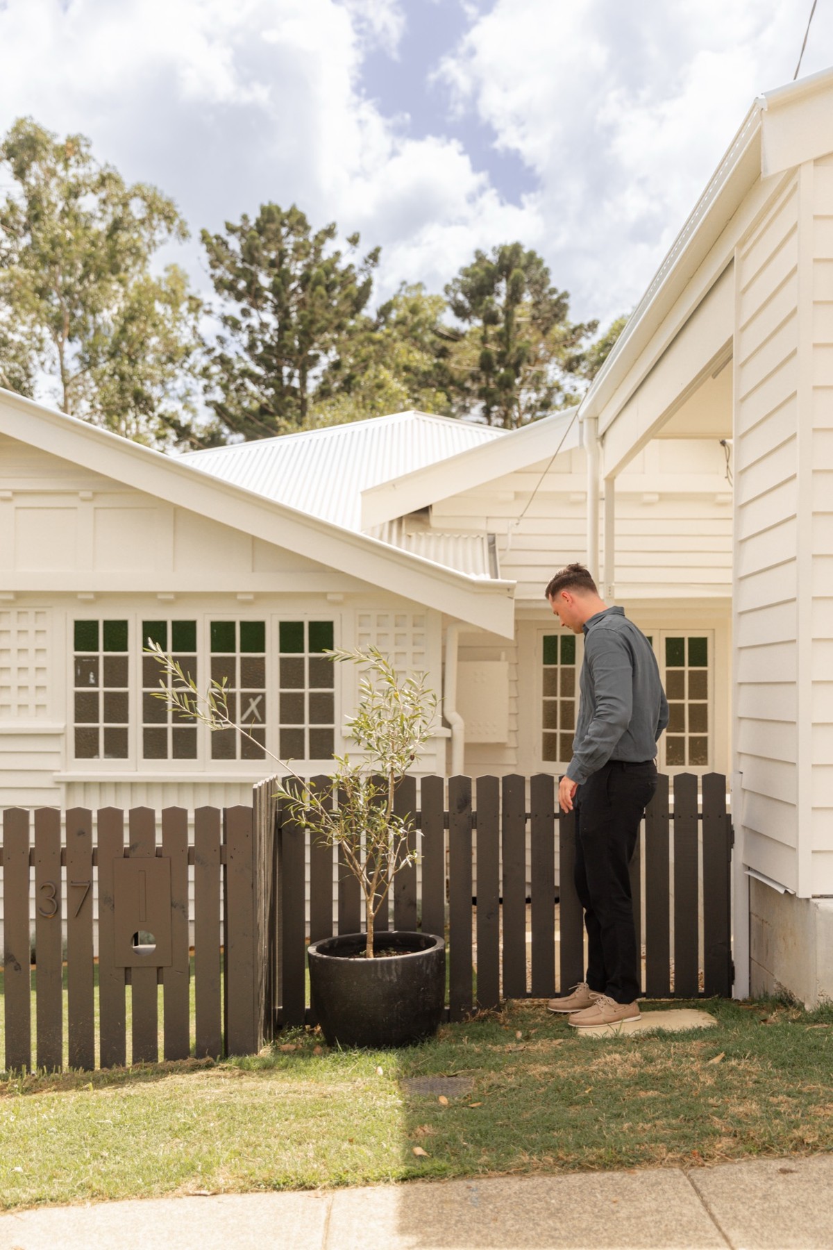 Jack Freestone beside a timber gate outside a white weatherboard house.