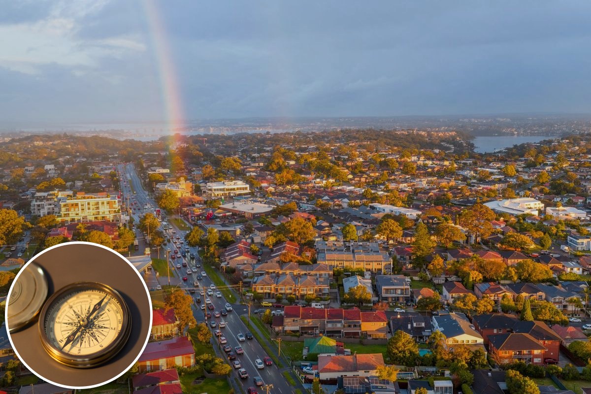 An aerial view of Australian suburbs along an arterial road, with a rainbow over the rooftops.