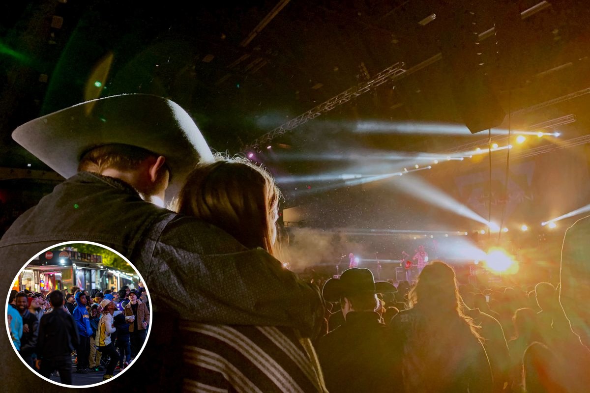 A crowd watching a band on an outdoor stage at night, lit by white and orange stage lights.