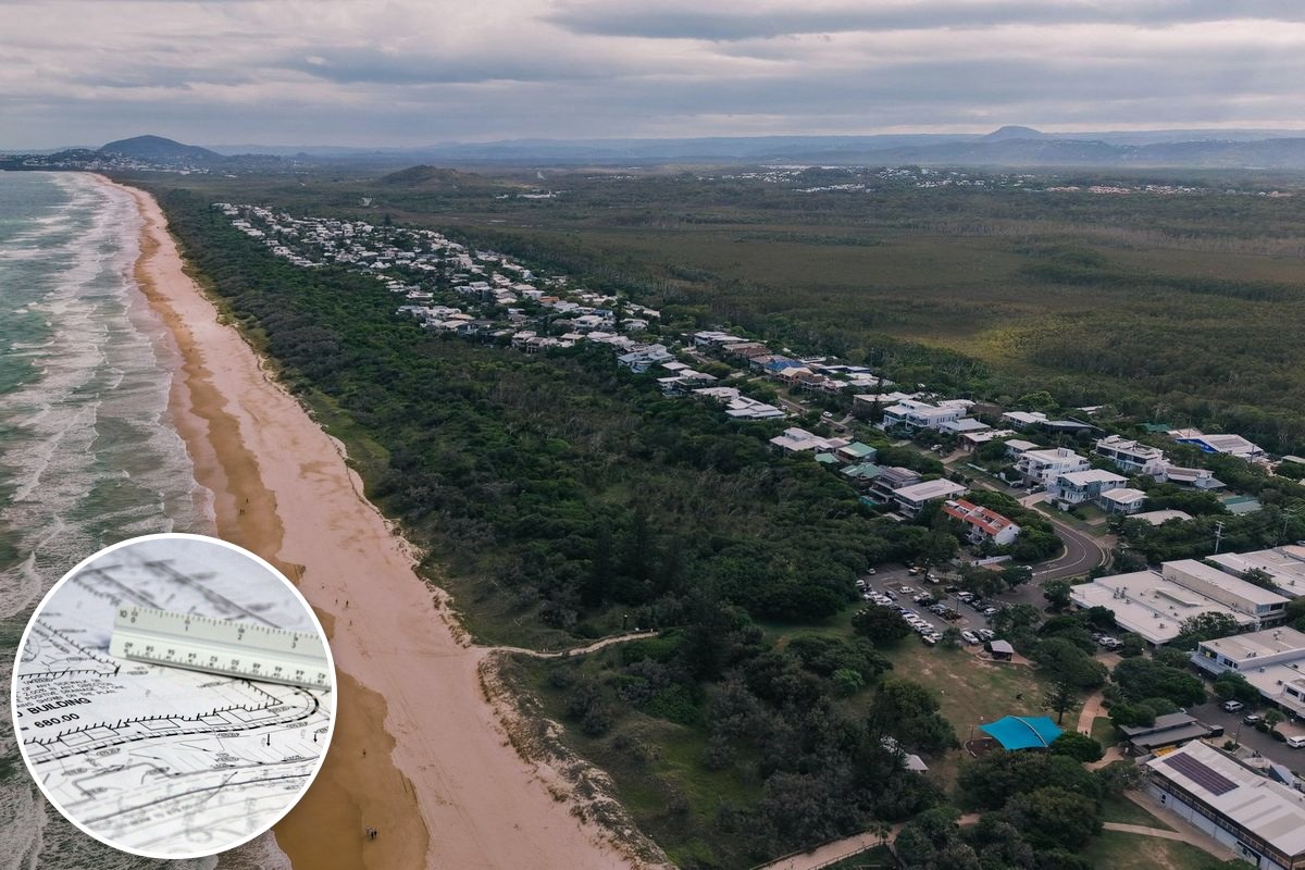 An aerial view of a Queensland coastal suburb, with rows of houses between bushland and the beach.