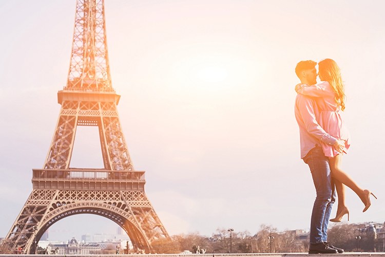 A couple embracing near the Eiffel Tower at sunset.