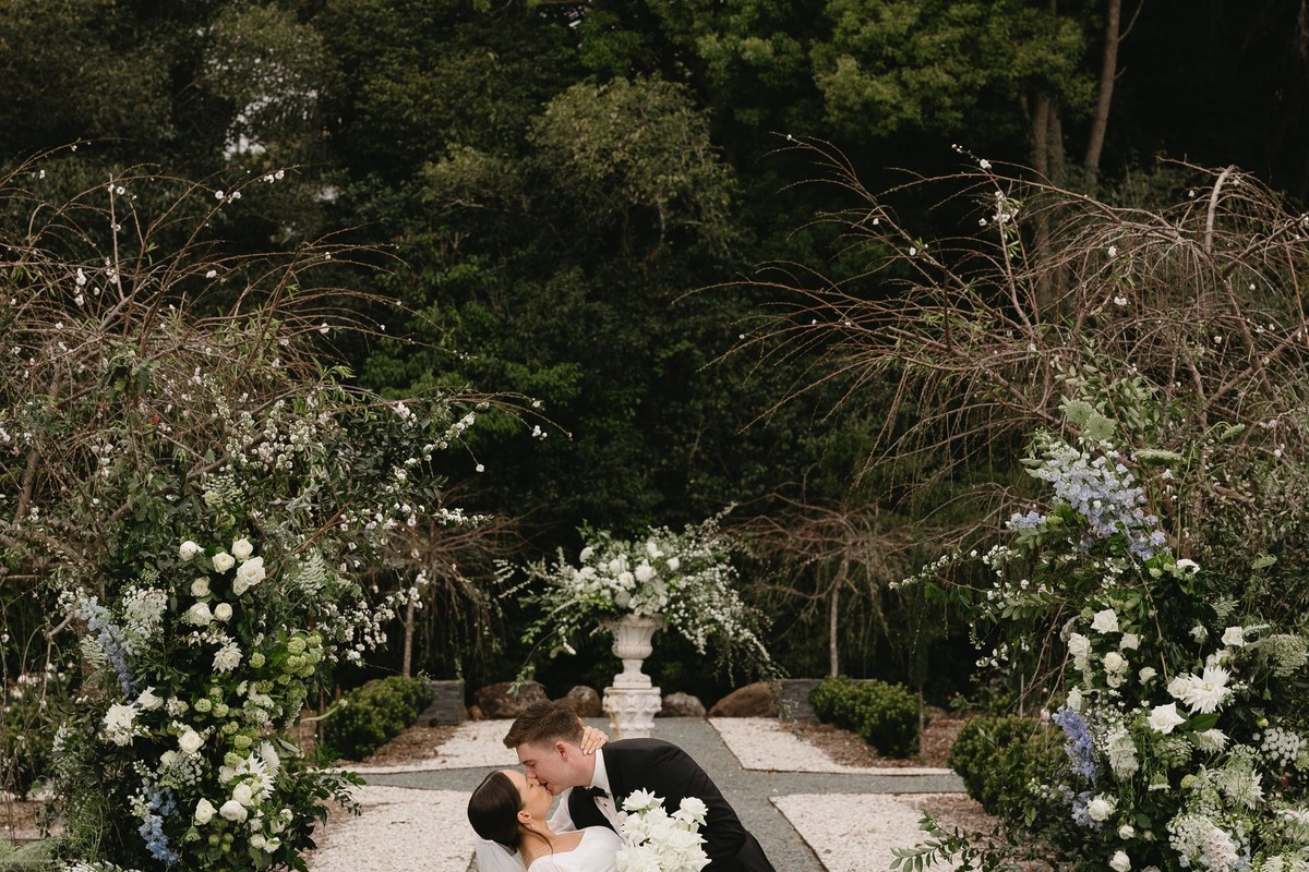 A couple kiss between floral arbors on the white-gravel paths of the parterre garden.